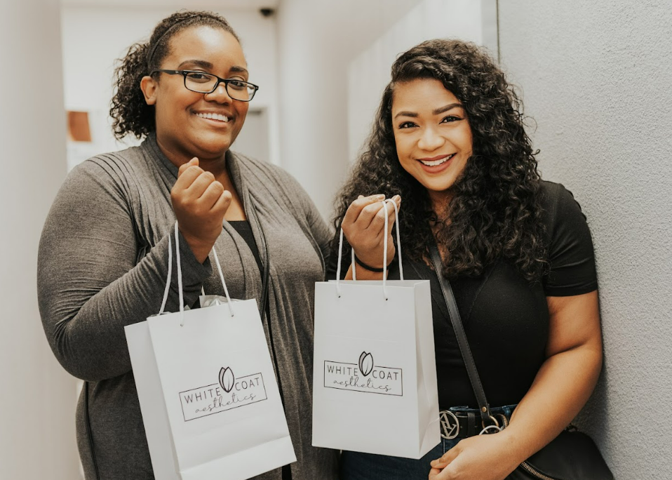 Two ladies holding package from White Coat Aesthetics | Medspa in Las Vegas, NV