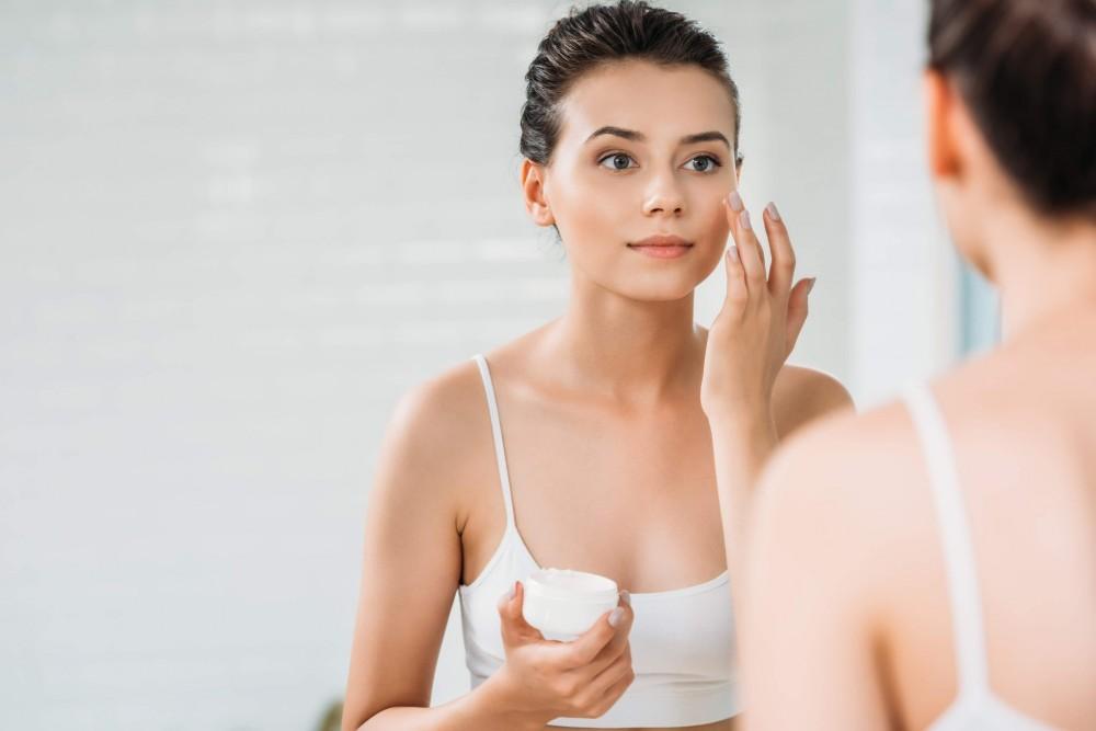 Close up beauty portrait of healthy beautiful half naked woman applying face cream looking at mirror | White Coat Aesthetics in Las Vegas, NV